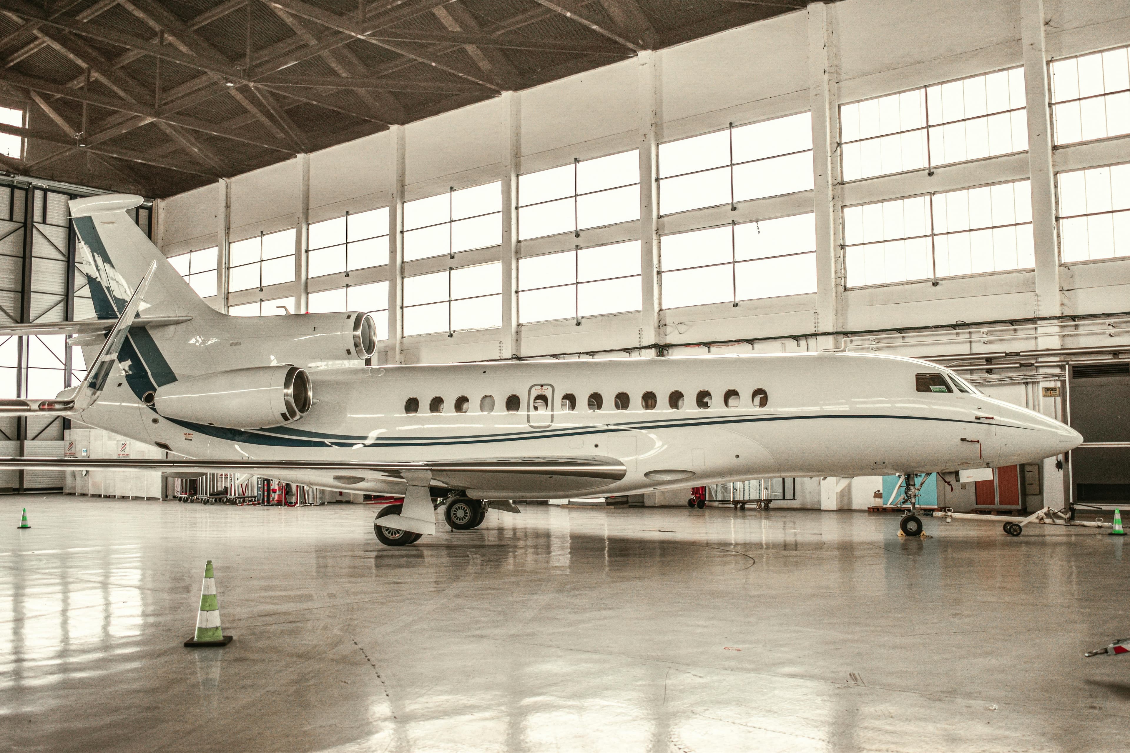 A super-midsize private jet parked on the FBO ramp at Opa-locka Executive Airport at dusk with palm trees in the background