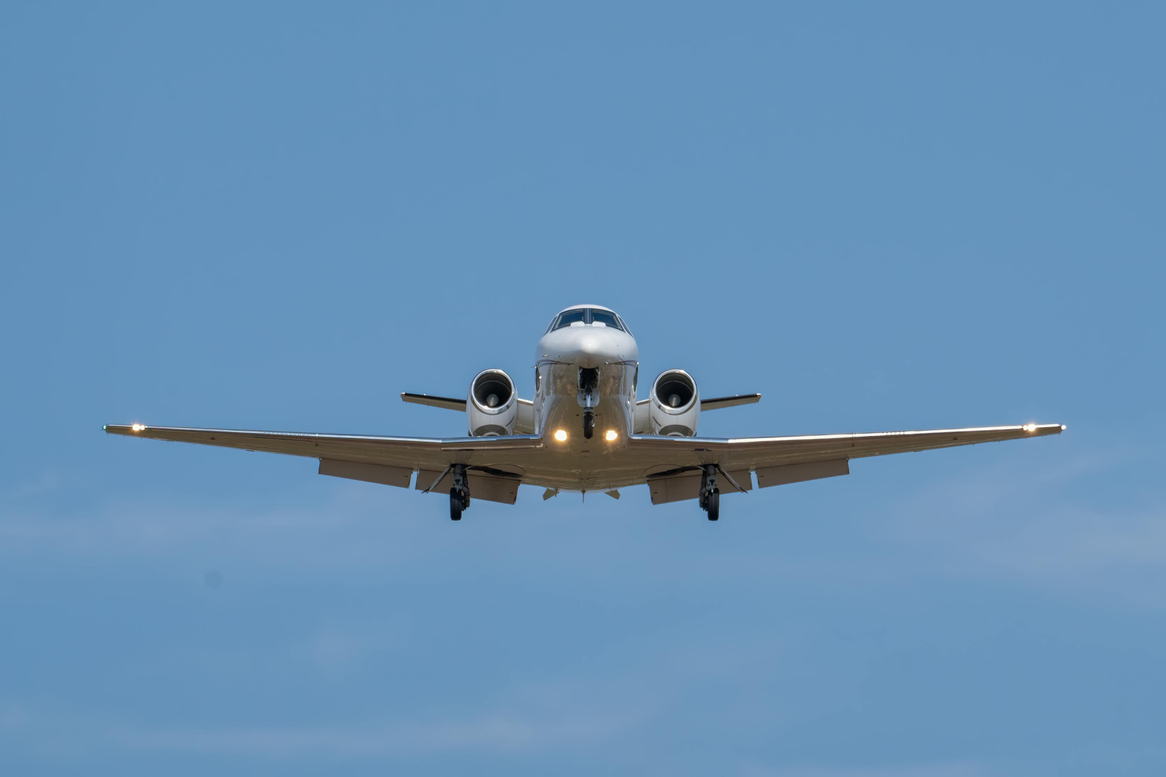 A light jet parked on the ramp at Naples Municipal Airport with palm trees and a Florida sky in the background