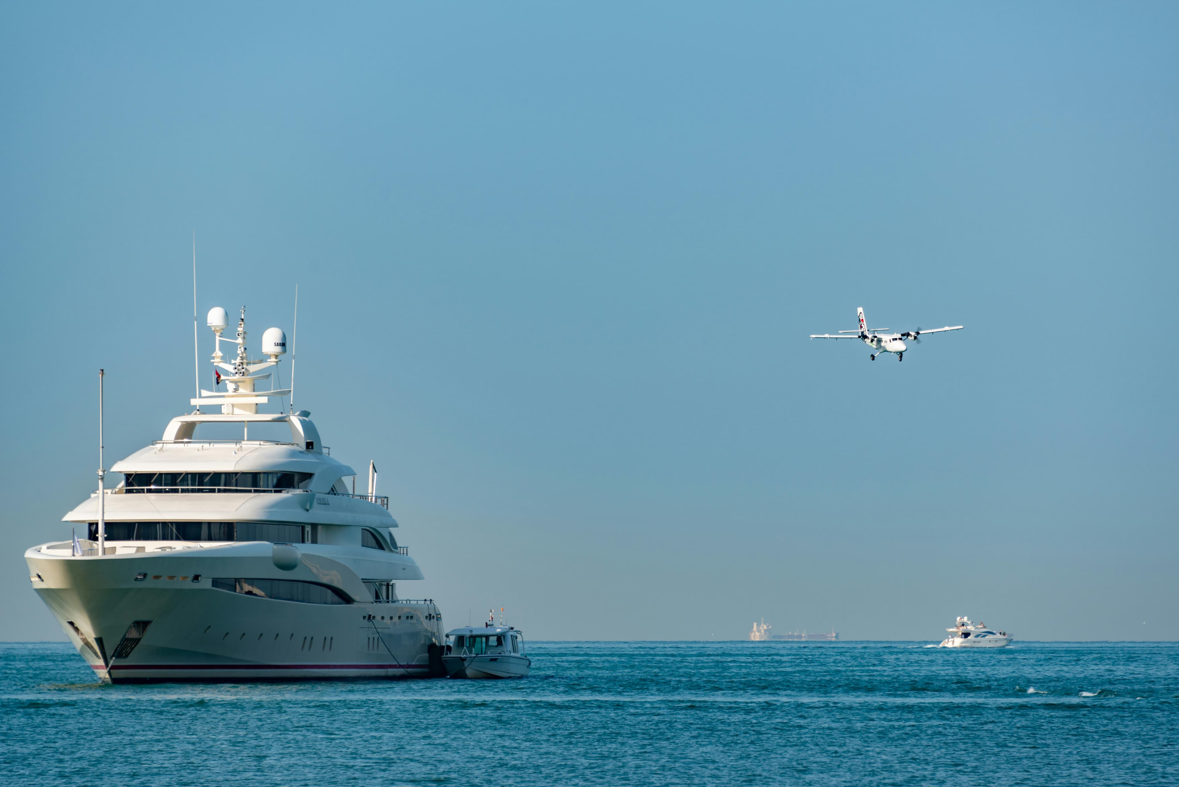 A motor yacht at anchor in clear turquoise water with a tender deployed off the swim platform