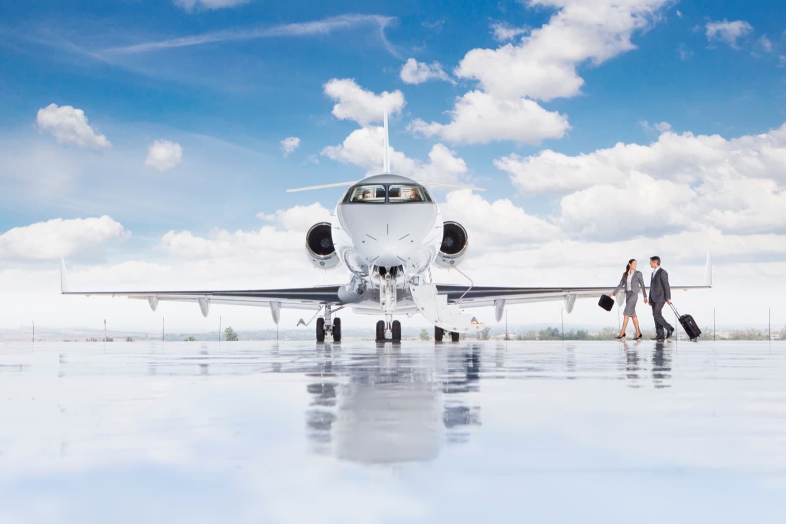 A super-midsize private jet parked on a snow-cleared ramp at a mountain airport with peaks rising behind it