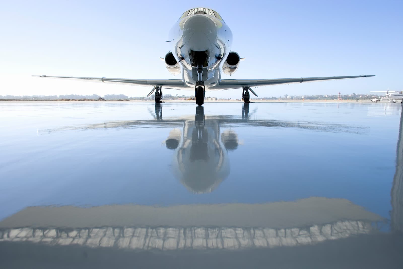 A light jet on the ramp at a Louisville FBO at golden hour with a black chauffeur sedan staged at the cabin door