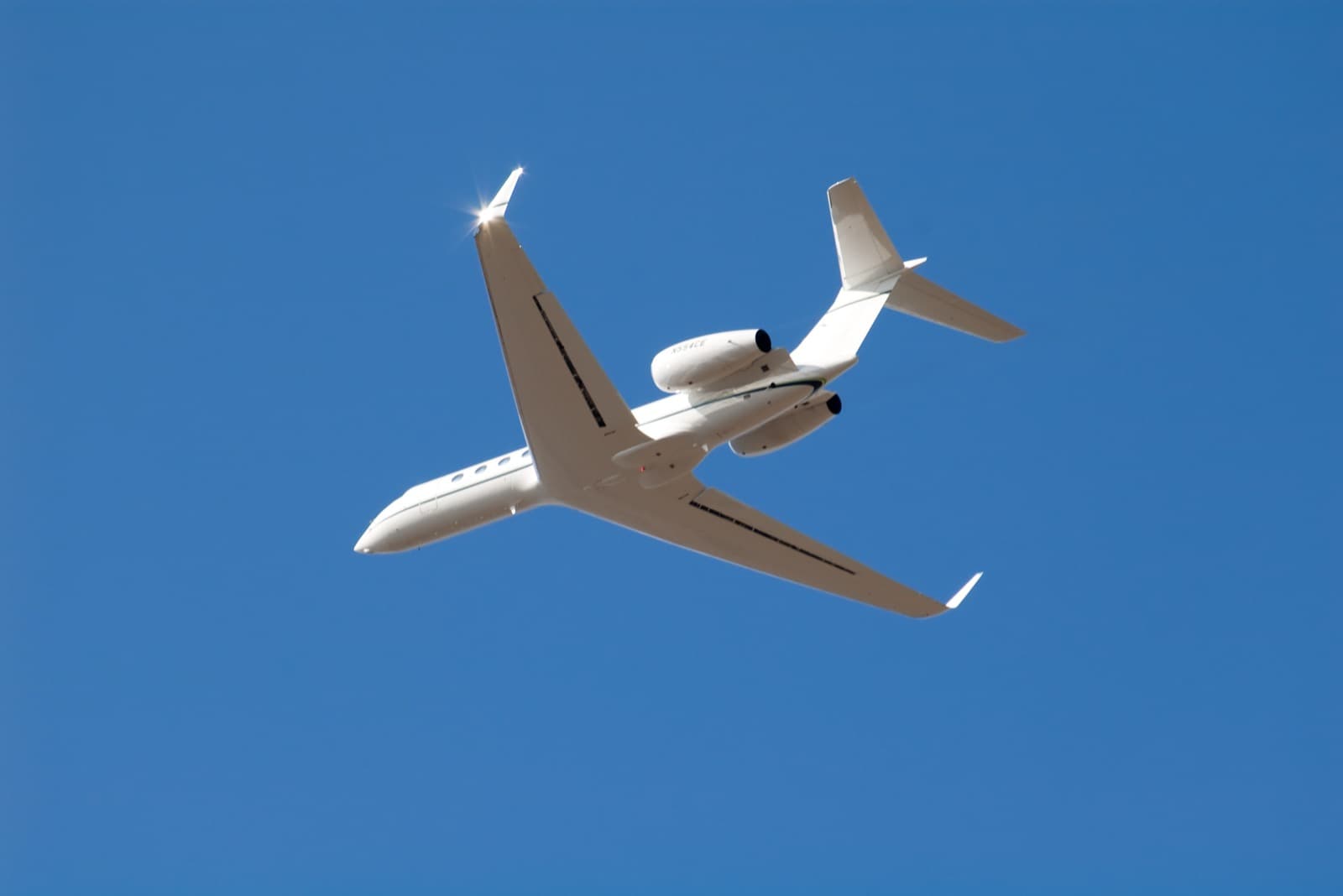 A super-midsize private jet on short final to a mountain runway at Aspen with snow-streaked peaks behind